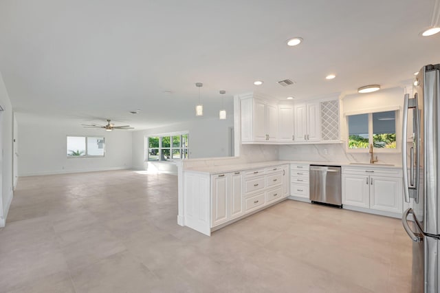 kitchen featuring a peninsula, stainless steel appliances, open floor plan, light countertops, and decorative light fixtures