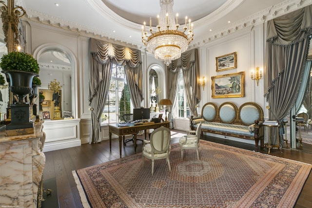 living area featuring a raised ceiling, dark wood finished floors, crown molding, a chandelier, and a decorative wall