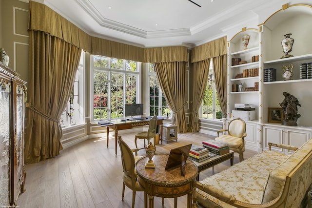 living area featuring ornamental molding, a tray ceiling, a wealth of natural light, and light wood-style floors