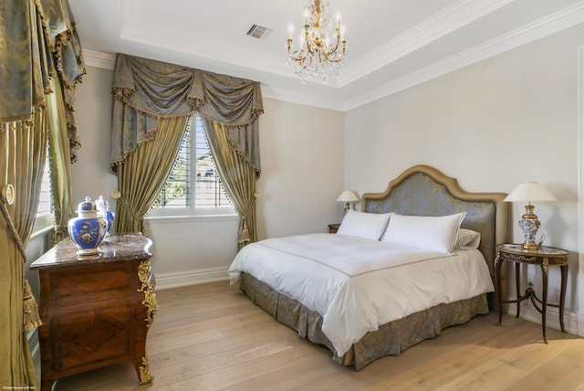 bedroom featuring light wood-style floors, a tray ceiling, visible vents, and ornamental molding