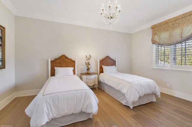 bedroom with light wood-style flooring, crown molding, baseboards, and a notable chandelier