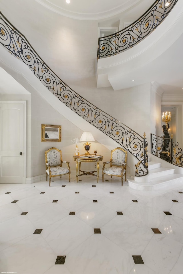 stairs with ornamental molding, a towering ceiling, and a notable chandelier