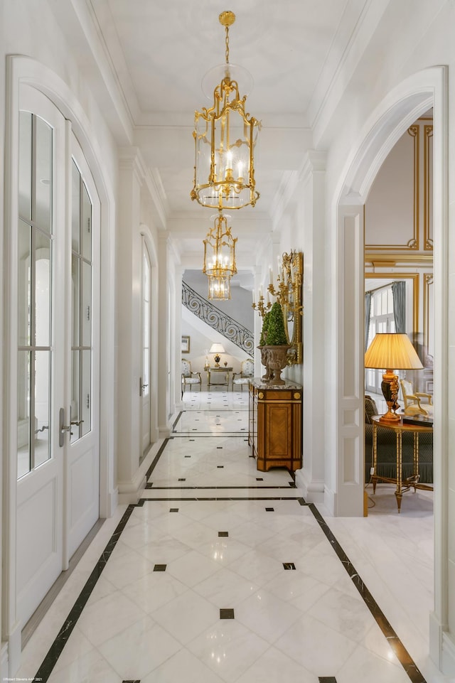 hallway with french doors, crown molding, baseboards, and an inviting chandelier