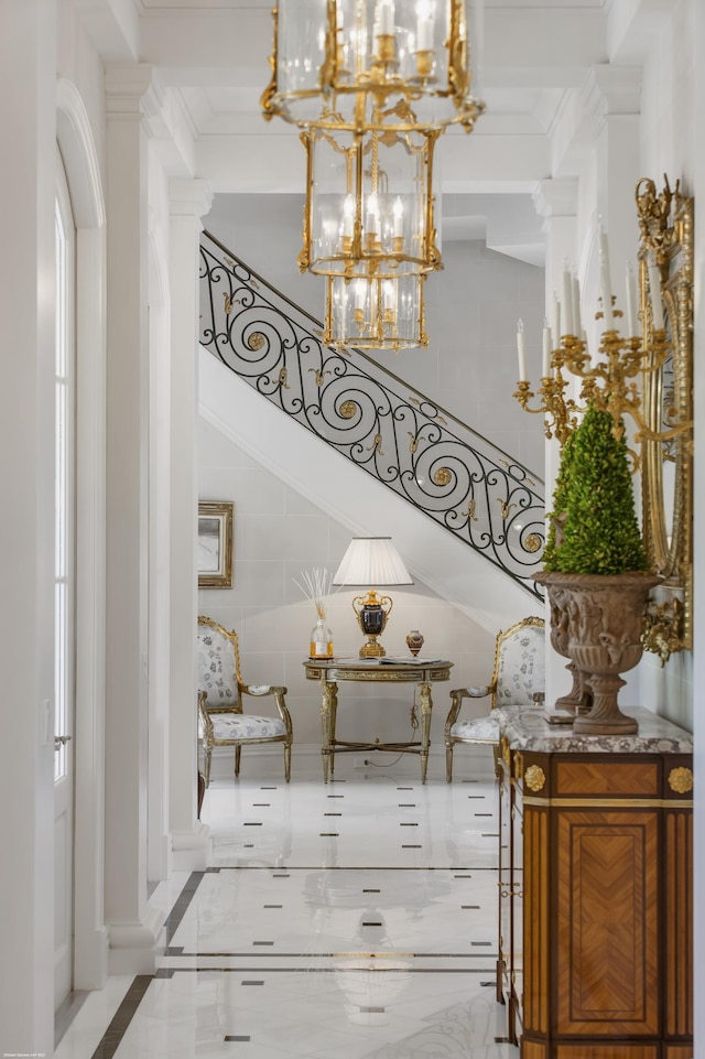 interior space featuring a chandelier, marble finish floor, crown molding, and ornate columns