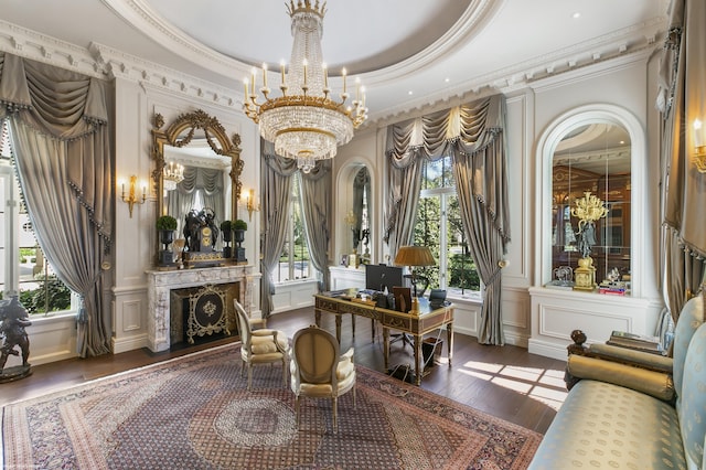 living area featuring plenty of natural light, a raised ceiling, a decorative wall, and an inviting chandelier