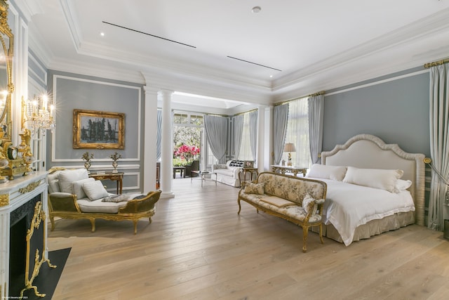 bedroom featuring decorative columns, a raised ceiling, ornamental molding, a high end fireplace, and light wood-type flooring