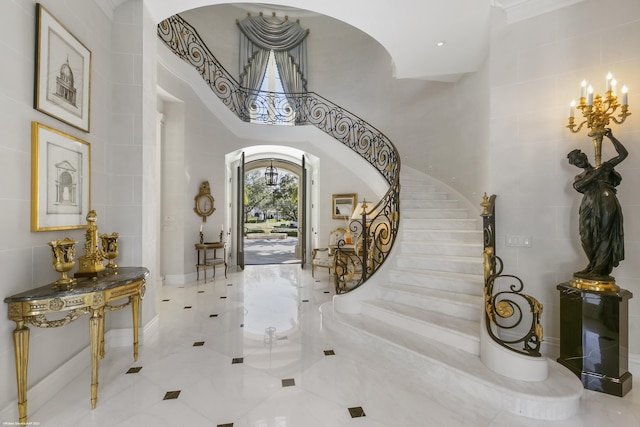 entryway with arched walkways, stairway, a chandelier, and a towering ceiling