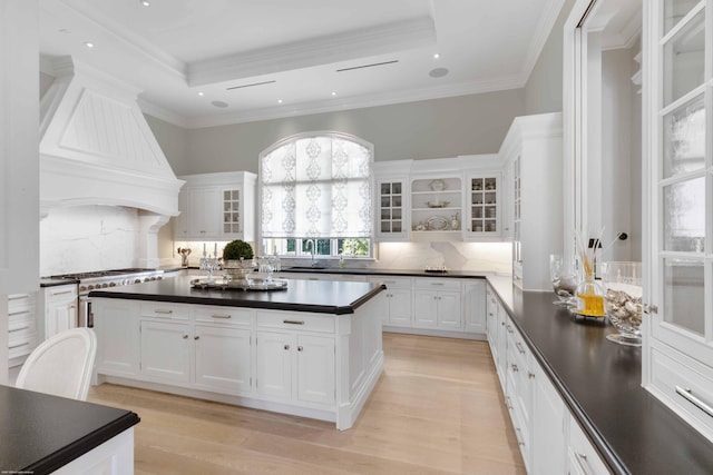 kitchen with glass insert cabinets, dark countertops, and white cabinetry