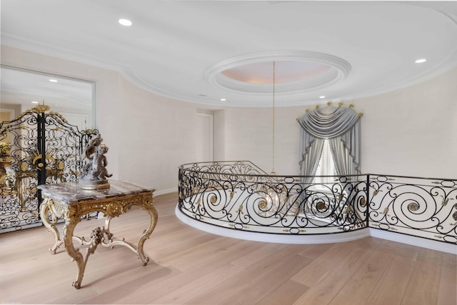 corridor featuring light wood-style flooring, ornamental molding, and an upstairs landing