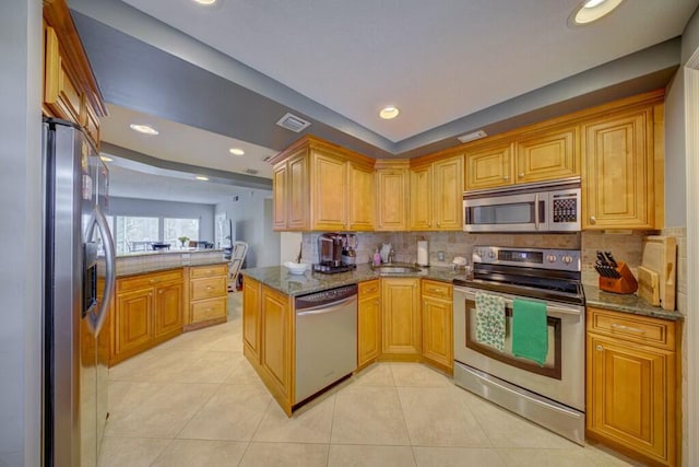 kitchen featuring tasteful backsplash, appliances with stainless steel finishes, dark stone countertops, and light tile patterned flooring