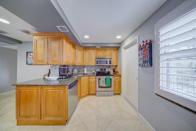 kitchen featuring tasteful backsplash, visible vents, dark stone counters, stainless steel appliances, and a sink