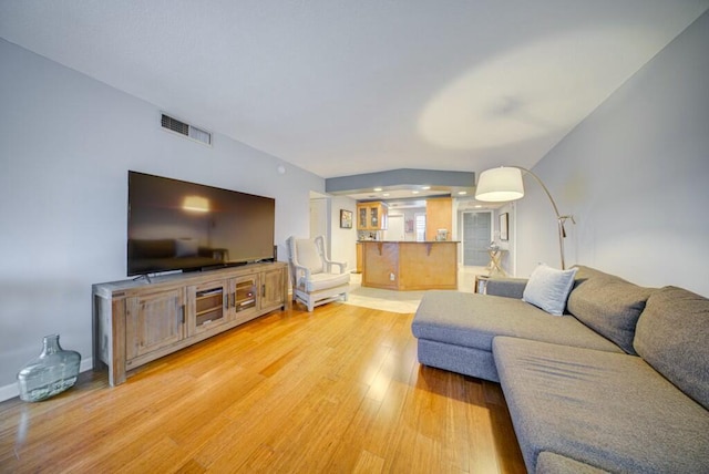 living area featuring baseboards, visible vents, and light wood finished floors