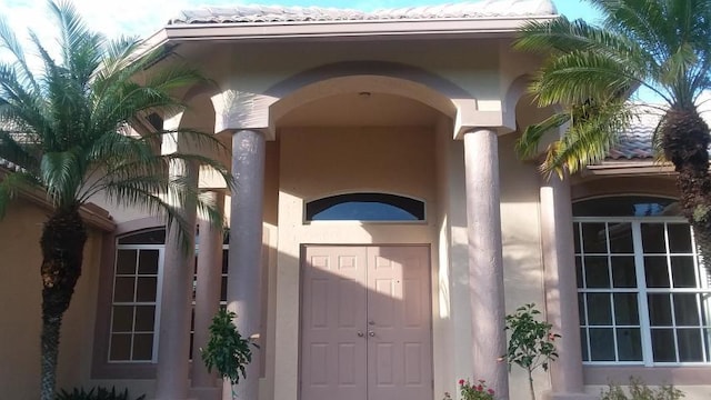 property entrance with a tile roof and stucco siding