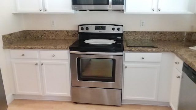 kitchen with white cabinetry, appliances with stainless steel finishes, and dark stone counters