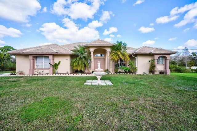 mediterranean / spanish-style house featuring a tiled roof, a front lawn, and stucco siding