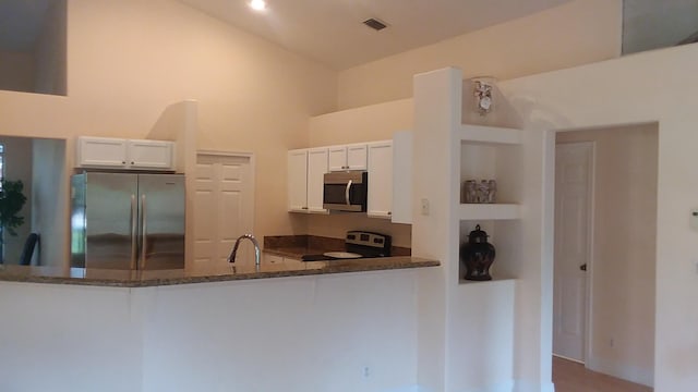 kitchen with visible vents, appliances with stainless steel finishes, white cabinetry, dark stone countertops, and a peninsula