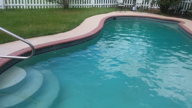 view of swimming pool with a lawn, fence, and a fenced in pool