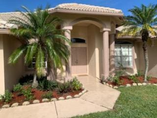 doorway to property with a tiled roof, a lawn, and stucco siding