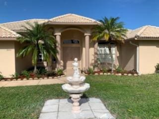 mediterranean / spanish house featuring a tiled roof, a front lawn, and stucco siding