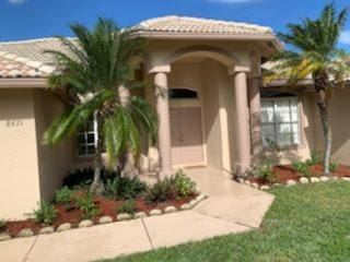 doorway to property featuring a yard, a tile roof, and stucco siding