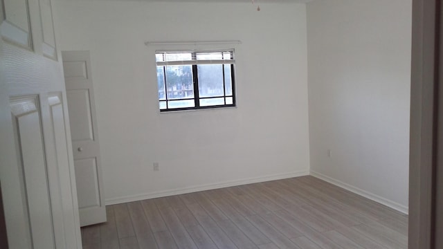 empty room featuring light wood-type flooring and baseboards