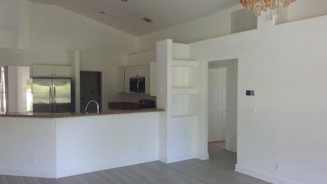 kitchen featuring a peninsula, dark wood-type flooring, a sink, visible vents, and appliances with stainless steel finishes