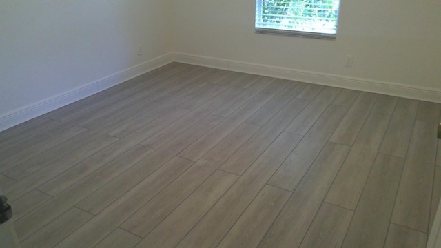 spare room featuring light wood-style floors and baseboards