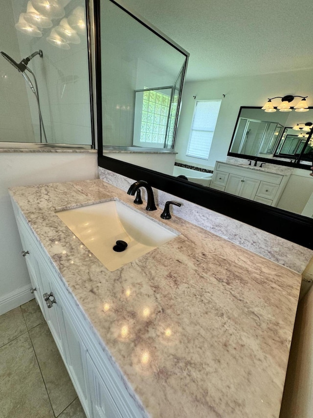 full bath with tile patterned floors, walk in shower, a textured ceiling, and vanity