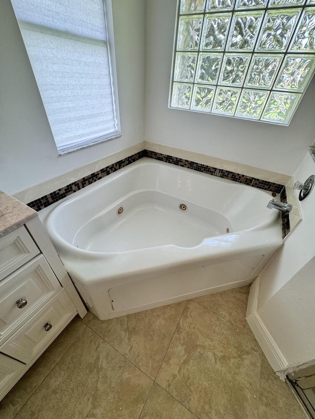 bathroom featuring a healthy amount of sunlight, tile patterned flooring, a jetted tub, and vanity