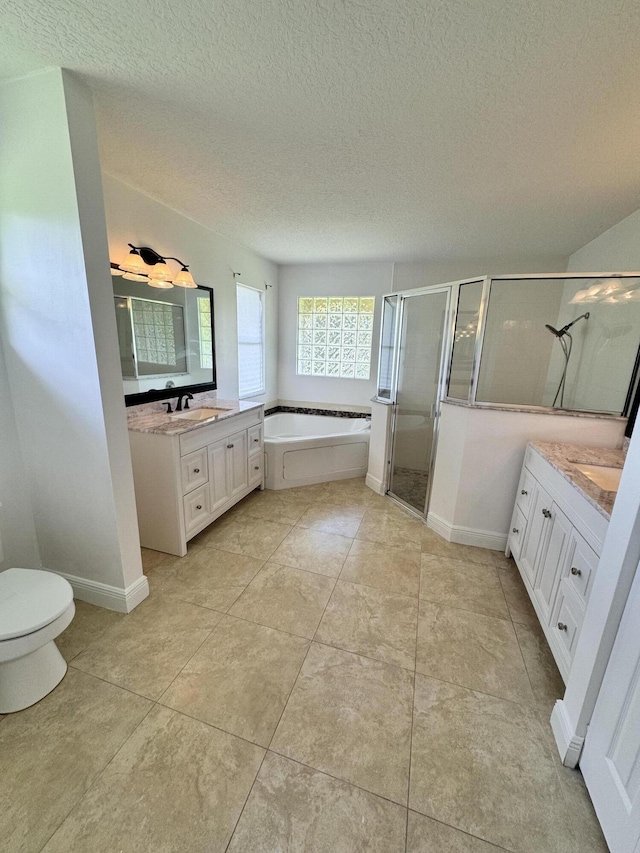 bathroom with two vanities, a garden tub, a textured ceiling, a shower stall, and a sink