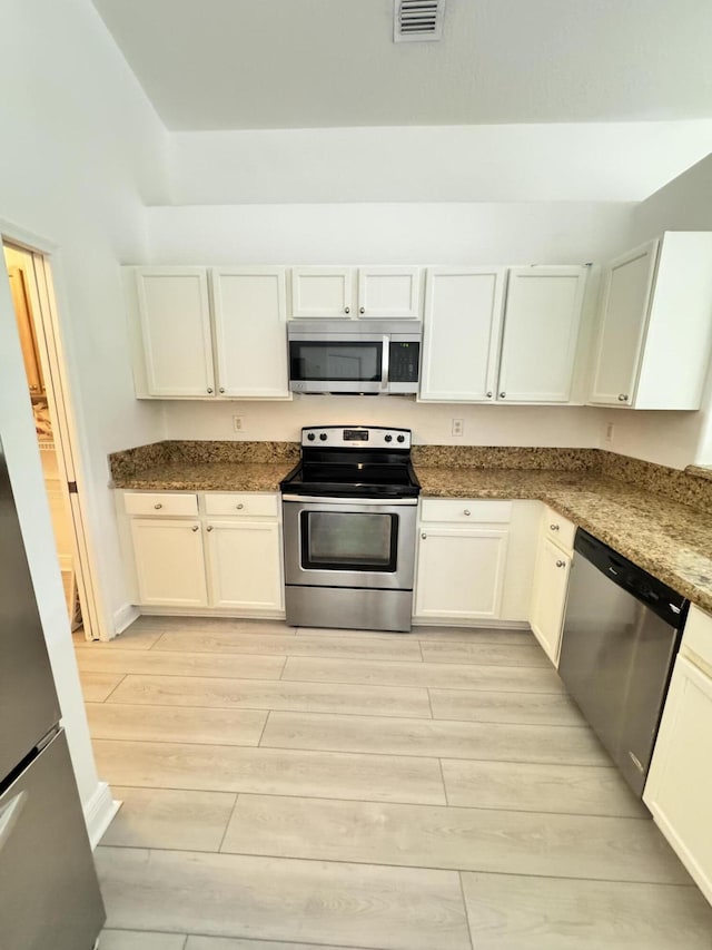 kitchen featuring appliances with stainless steel finishes, white cabinets, and visible vents