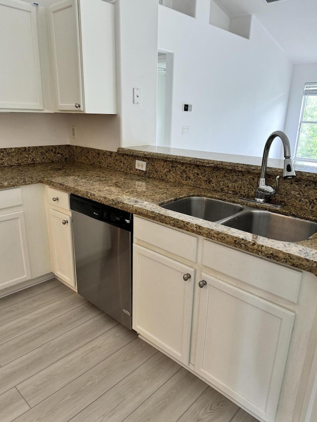 kitchen featuring light wood-style flooring, white cabinetry, a sink, dark stone countertops, and dishwasher