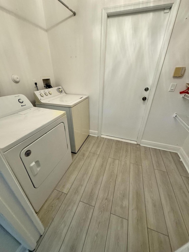 laundry room with baseboards, laundry area, light wood-type flooring, and washer and dryer