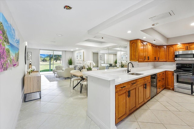 kitchen featuring stainless steel appliances, visible vents, brown cabinetry, light tile patterned flooring, and a sink