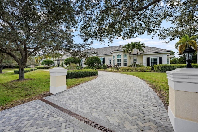 view of front of home with decorative driveway and a front lawn