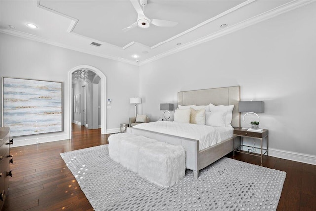 bedroom with dark wood-type flooring, arched walkways, crown molding, and baseboards