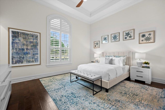 bedroom with crown molding, ceiling fan, baseboards, a tray ceiling, and hardwood / wood-style flooring