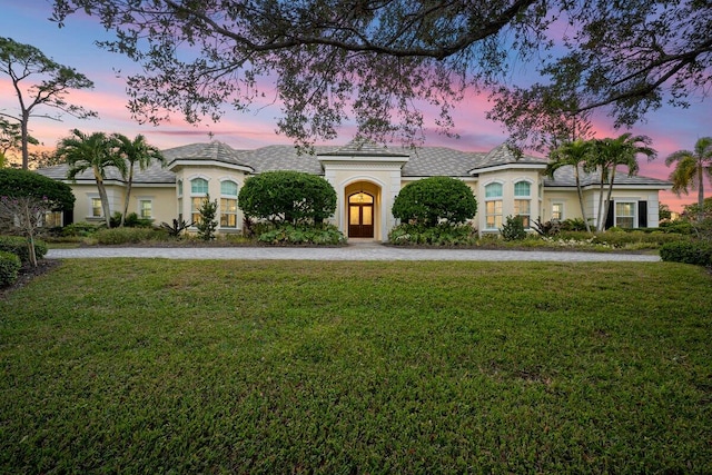 french provincial home with a yard and stucco siding