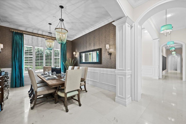 dining area with wallpapered walls, decorative columns, arched walkways, crown molding, and a decorative wall