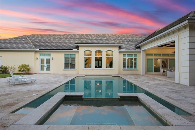 back of property featuring stucco siding, a patio, french doors, and a pool with connected hot tub