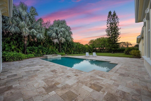 pool at dusk with an outdoor pool, a patio area, and a jacuzzi