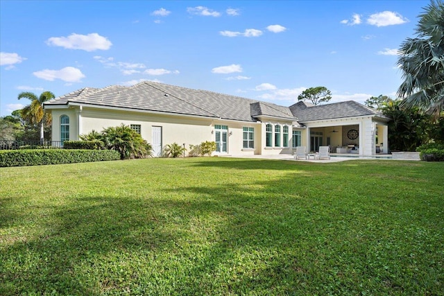 rear view of house featuring stucco siding, a lawn, a patio, and fence