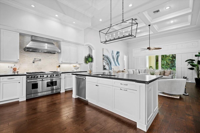 kitchen featuring dark countertops, visible vents, wall chimney range hood, appliances with stainless steel finishes, and coffered ceiling