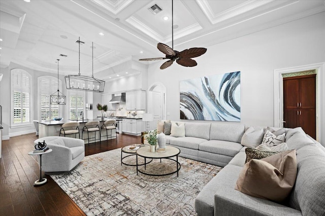 living area with dark wood-style flooring, crown molding, visible vents, and coffered ceiling