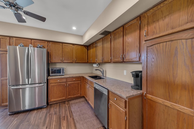 kitchen featuring stainless steel appliances, dark wood-style flooring, a sink, visible vents, and brown cabinetry