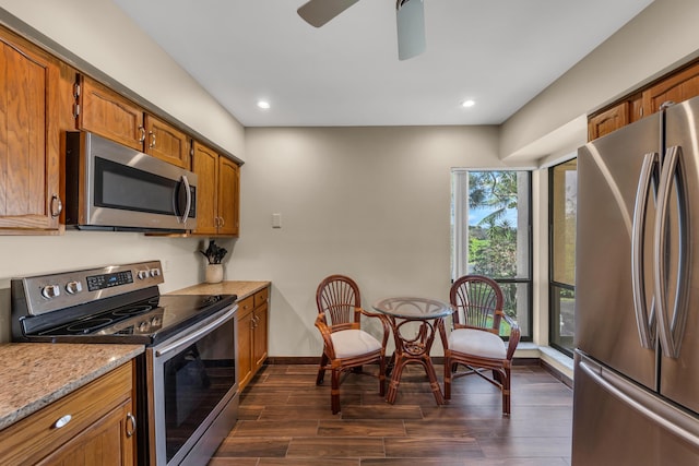 kitchen featuring baseboards, brown cabinetry, appliances with stainless steel finishes, dark wood-style flooring, and recessed lighting