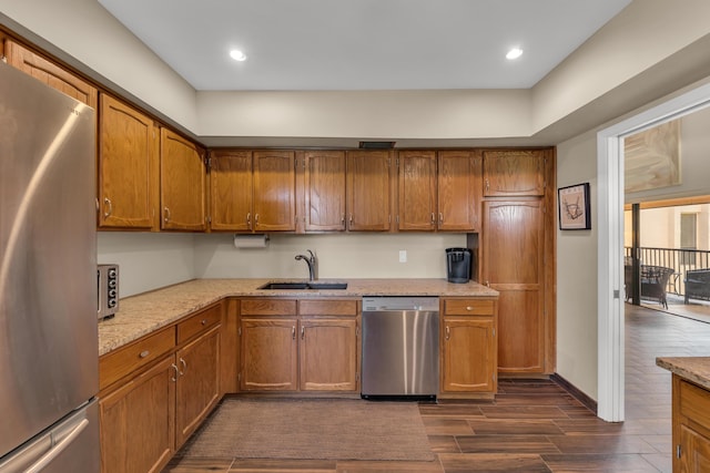 kitchen with dark wood-style flooring, appliances with stainless steel finishes, brown cabinets, and a sink