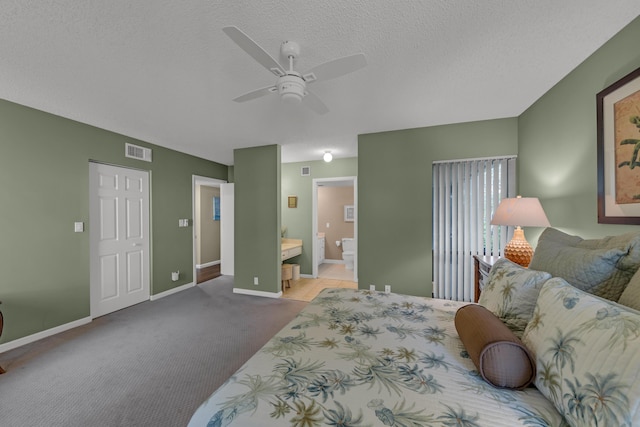 bedroom with baseboards, visible vents, ensuite bath, a textured ceiling, and carpet flooring