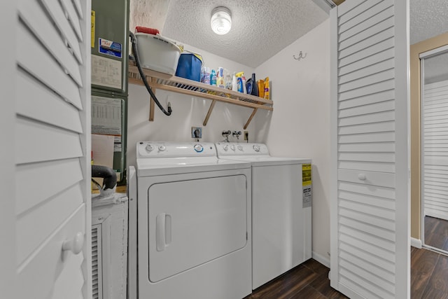 clothes washing area with dark wood finished floors, washing machine and dryer, a textured ceiling, laundry area, and baseboards