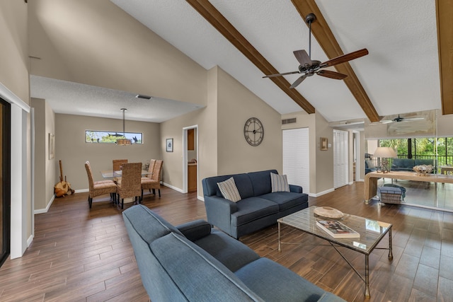 living area featuring a healthy amount of sunlight, a textured ceiling, wood finished floors, and beamed ceiling